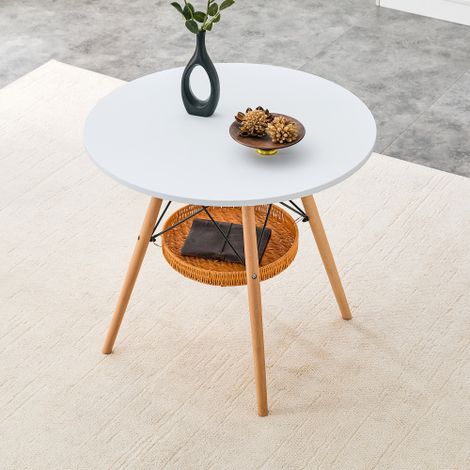 Runder Esstisch Ø 80 cm, Tischplatte aus weißem MDF, Tischbeine aus Massivholz, kombiniert mit einer schwebenden, geflochtenen Ablagekorbkonstruktion, geeignet für 2 bis 4 Personen.