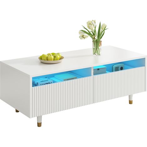 Cette table basse moderne à LED est dotée d'un plateau à tiroirs ondulé, de pieds dorés et blancs, de deux tiroirs et d'une bande lumineuse LED à couleurs changeantes. Un meuble TV assorti est égaleme