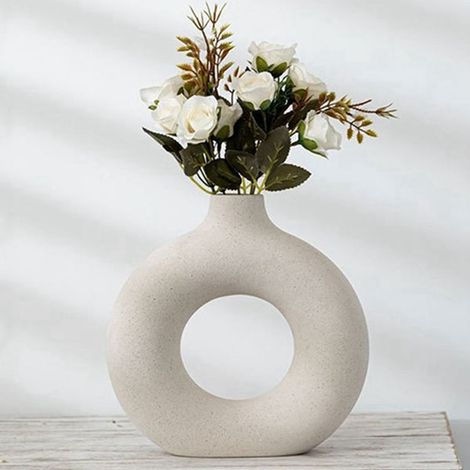 Eine runde, cremefarbene Keramikvase im nordischen Stil, ein kreatives Dekorationsobjekt für das Wohnzimmer.