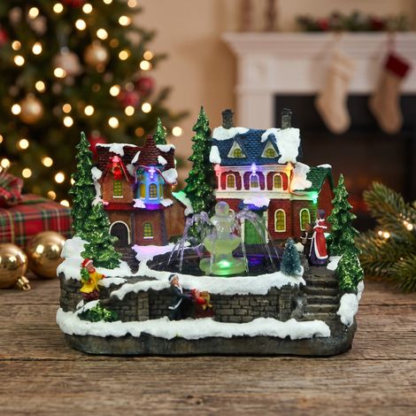 Pueblo Navideño Luminoso con Casas y Fuente de Agua