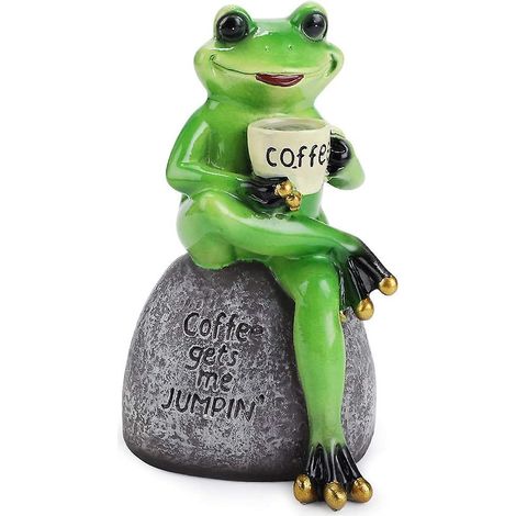 Froschfigur aus Kunstharz sitzt auf einem Stein, niedliche, kreative und lustige grüne Froschskulptur, die Kaffee trinkt.