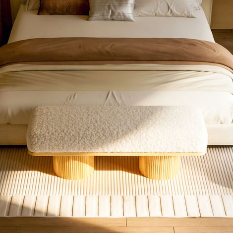 Banc moderne et moelleux, avec un socle en bois massif. Assise tapissée de duveteux tissus en fausse fourrure. Idéal pour l’entrée du lit. Design en couleur crème. (1/5)