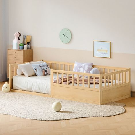 Cama infantil a ras de suelo de pino macizo natural, 90x200 cm, con barandillas de seguridad y somier de láminas incluido.