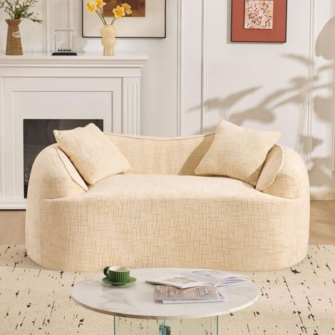 Canapé deux places beige incurvé avec accoudoirs et deux coussins de dossier. Idéal pour les petits appartements, les salons ou les chambres. (1/5)