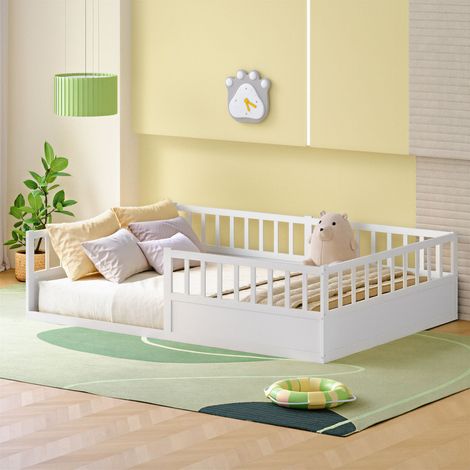 Cama infantil a ras de suelo de pino blanco macizo, 140x200 cm, con barandillas de seguridad y somier de láminas incluido.