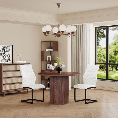 CAIziUne table à manger ronde de 100 cm avec deux chaises blanches.