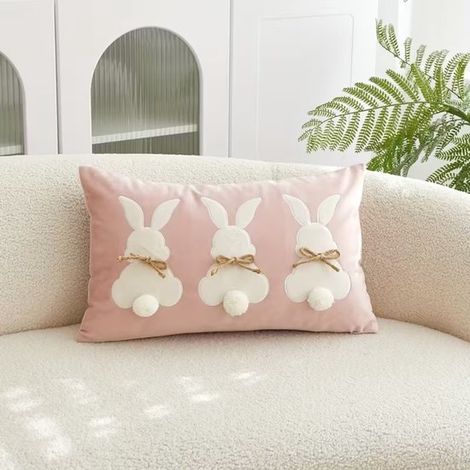 Coussin décoratif en velours rose avec 3 lapins – Coussin décoratif de luxe avec nœuds et pompons – 30 x 50 cm – Décoration pour chambre d'enfant / Pâques / Accessoires pour la maison (1/3)