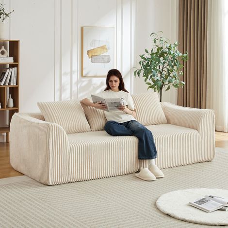 Divano minimalista in velluto a coste da 235 cm con linee curve e schienale leggermente inclinato, completo di due cuscini.