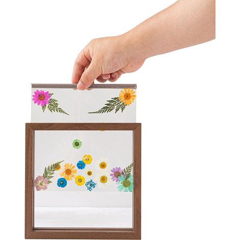 Marco de madera con frontal de cristal, decorado con flores y hojas secas, ideal para una foto de boda o para decorar una oficina.