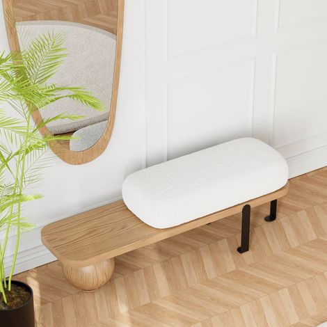 Le banc d'entrée est doté d'un coussin rond blanc moelleux et de pieds en métal aux formes géométriques.