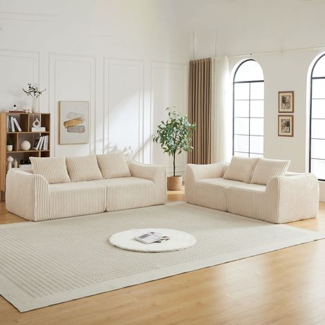 Divano minimalista in velluto a coste dalle linee eleganti, con schienale leggermente inclinato e cinque cuscini.
