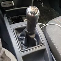 Dieses Set beinhaltet eine Staubschutzhülle für den Schaltknauf eines Volkswagen POLO, einen mit rotem Zierstich und silbernen Zierelementen versehenen Lederknauf sowie ein 5-Gang-Getriebe.