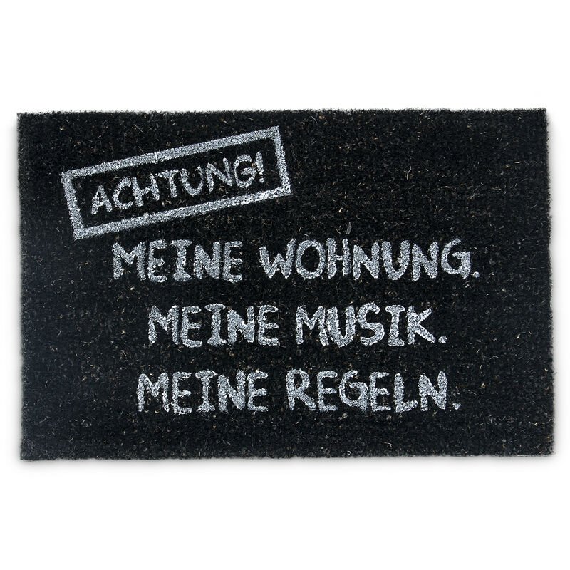 

– Felpudo “Achtung: Meine Wohnung, meine Musik, meine Regeln” para la entrada de su hogar hecho de fibras de coco y PVC con medidas 40 x 60 cm